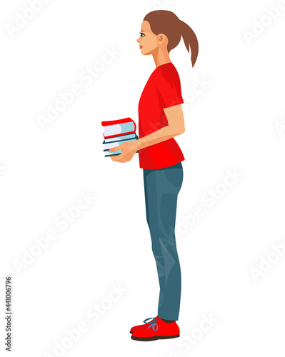 A teenage schoolgirl stands and holds a stack of books in her hands