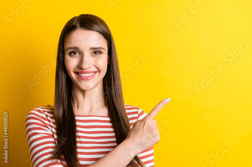 Portrait of attractive cheerful girl demonstrating copy empty space advert isolated over bright yellow color background