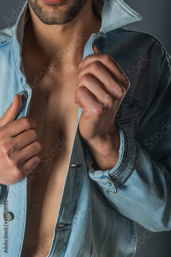 Picture of a young handsome macho man with abs and open denim jacket and jeans.