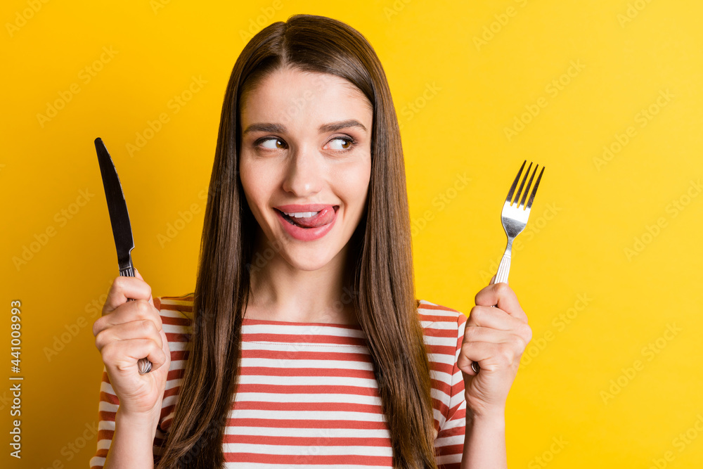 Portrait of attractive cheerful girlish hungry girl holding cutlery licking lip isolated over bright yellow color background Portrait of attractive cheerful girlish hungry girl holding cutlery licking lip isolated over bright yellow color background