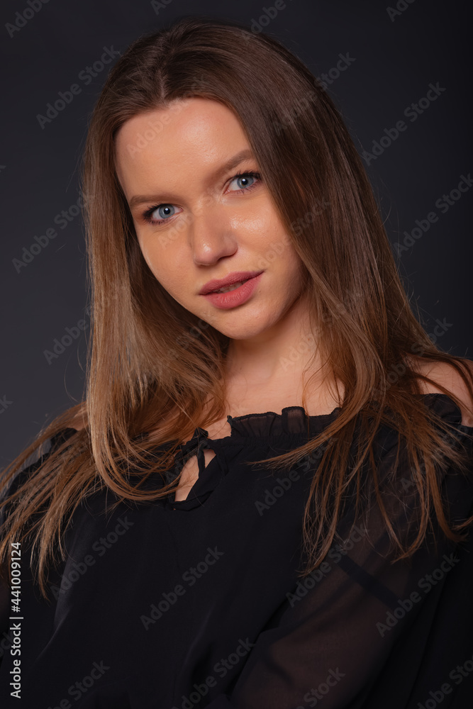 Close up portrait of a sexy female model looking serious while posing in black clothes inside a studio
