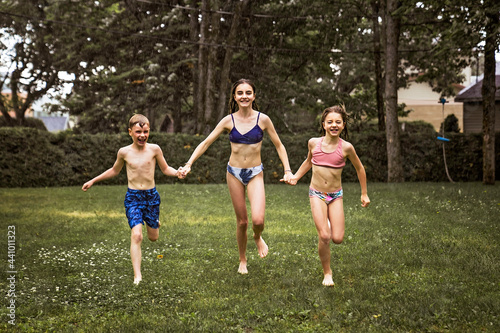Happy beautiful childs running through rain in Swimsuits