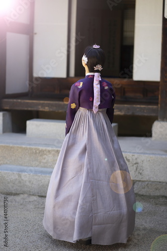 Woman in Korean traditional clothes standing at traditional Korean house
