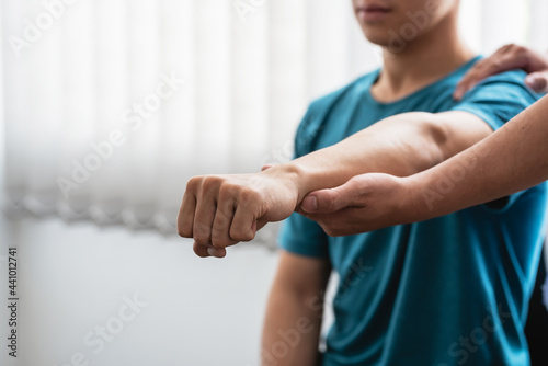 Physiotherapist treating a man with elbow pain at a clinic.
