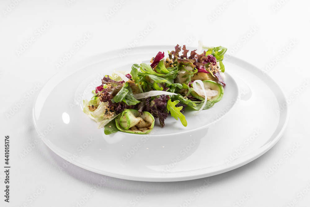 Grilled courgette with rocket salad and sesame seeds on white plate isolated on white background Grilled courgette with rocket salad and sesame seeds on white plate isolated on white background