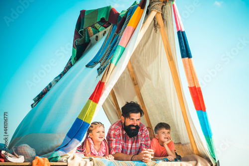 Father with kids children in tent. Summer outdoor vacation. Family playing together. Fathers day. photo