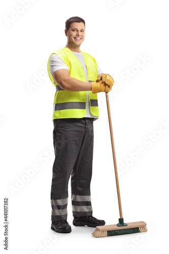 Full length portrait of a young male cleaner in a uniform holding a broom