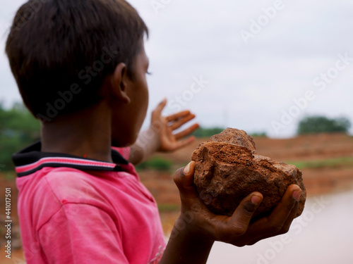 Картината върху платно Indian village boy throwing stone on river, Stone closeup on hand kids lifestyle concept
