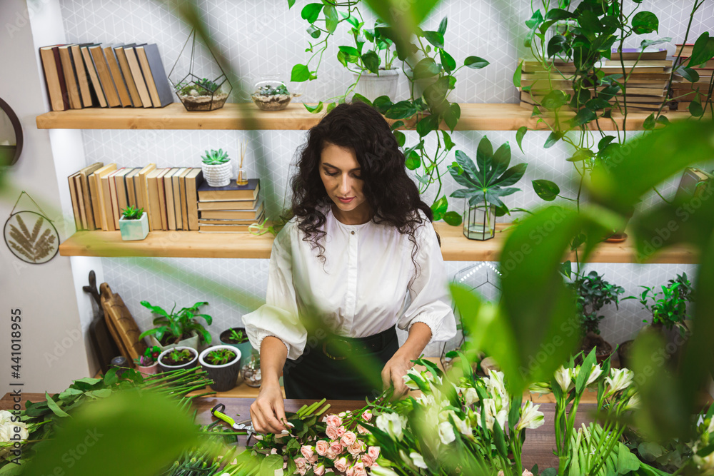 Attractive young woman florist is working in a flower shop. Attractive young woman florist is working in a flower shop.