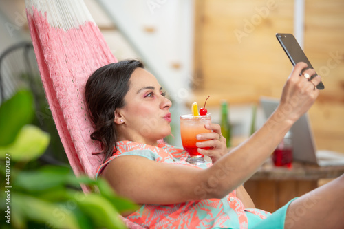 Mexican woman taking selfie on hammock on summer vacations