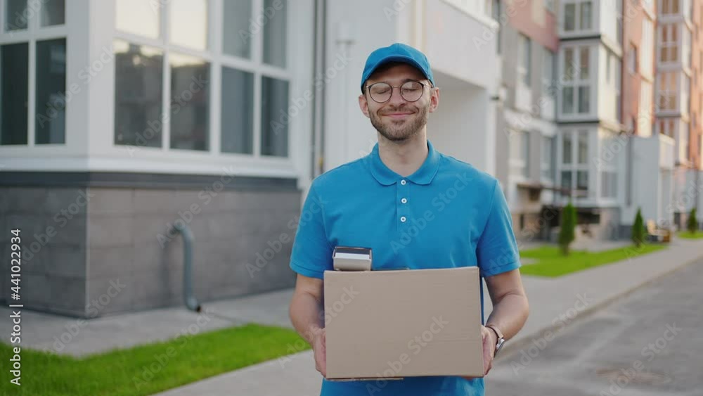 The bespectacled delivery guy looking at the camera smiles. The courier looks and smiles at the camera. Slow motion The bespectacled delivery guy looking at the camera smiles. The courier looks and smiles at the camera. Slow motion