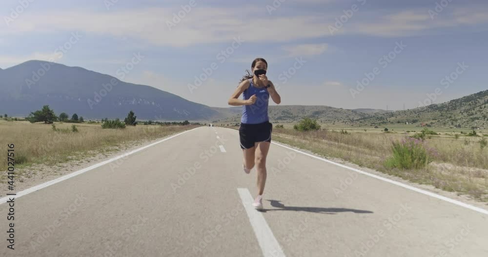 sporty woman with protective face mask running on countryside road in early morning sporty woman with protective face mask running on countryside road in early morning