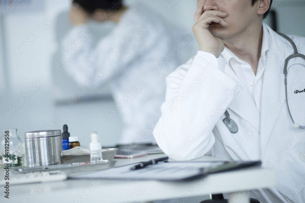 Pensive doctor sitting at desk in office Pensive doctor sitting at desk in office
