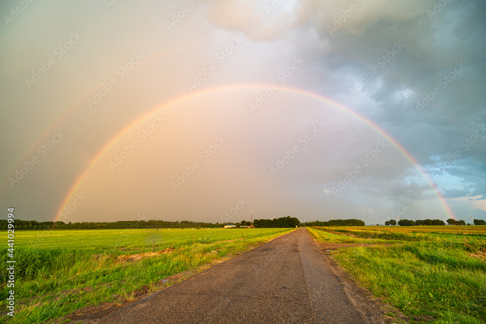 Bright double rainbow over a country road at the end of the day Bright double rainbow over a country road at the end of the day