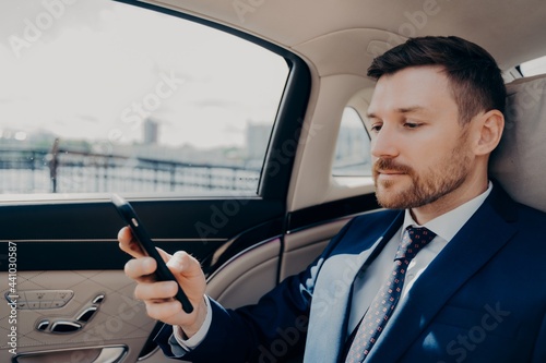 Investor checking his phone while riding in limousine