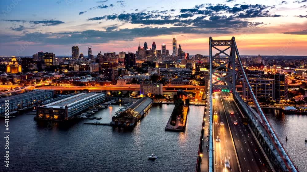 Aerial hyperlapse with Ben Franklin Bridge and Philadelphia skyline in transition from sunset to dusk. Ben Franklin Bridge is a suspension bridge connecting Philadelphia and Camden, NJ.