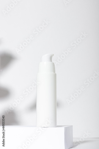 White cosmetic tube for cream, lotion, serum or face mask on the runway with leaf shadows. Professional cosmetics for skin care. Organic cosmetics.