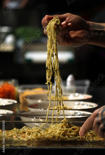 chef probando su plato de espaguetis cogiéndolo con palitos photo
