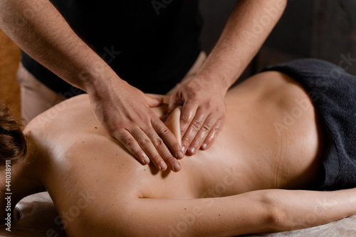 Attractive girl is relaxing on classic massage procedure in spa. Manual therapy. Masseur is doing back massage.
