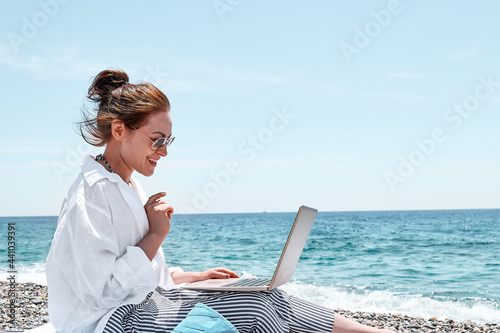 Canvas Print Pretty woman using laptop for online call at the beach