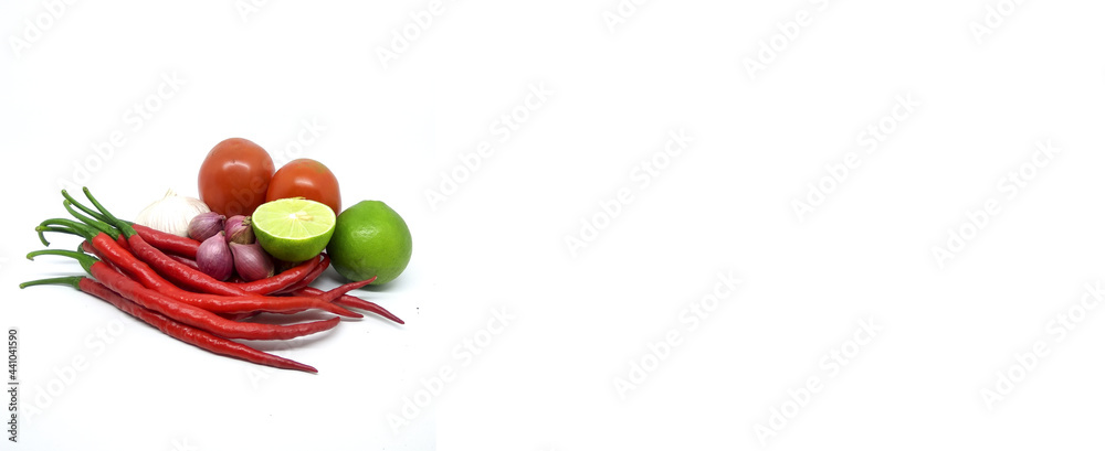 assorted kitchen spices consisting of red chilies, cayenne pepper, garlic and shallots, lime isolated on a white background