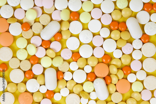 Many colored tablets of different shapes on a yellow background.
