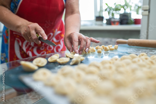 a woman makes homemade dumplings in the kitchen at the table