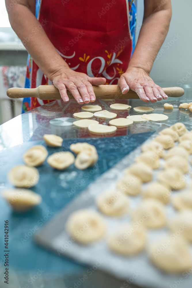 a woman makes homemade dumplings in the kitchen at the table.