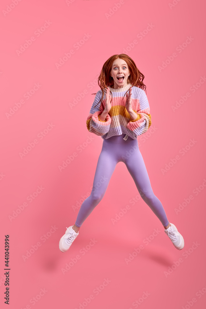 Caucasian redhead excited female jump at black friday discounts wear casual style outfit clothing isolated over pink color studio background, portrait. copy space