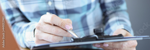 Manager sits at his desk and holds documents with pen photo