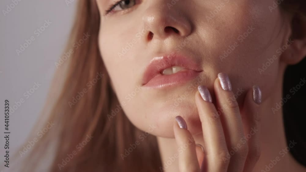 Facial skincare. Cleansing moisturizing. Beauty freshness. Relaxed satisfied pretty woman with nude makeup enjoying touching soft smooth radiant face skin isolated on beige.
