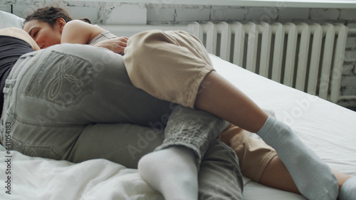 Teenagers are laying on white sheets in white room
