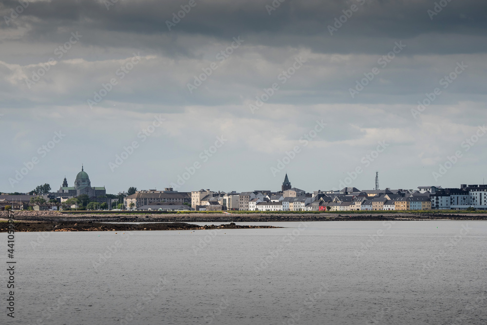 Galway Cathedral and The Long walk colorful houses. Cloudy sky. View from the ocean. Town famous landmark.