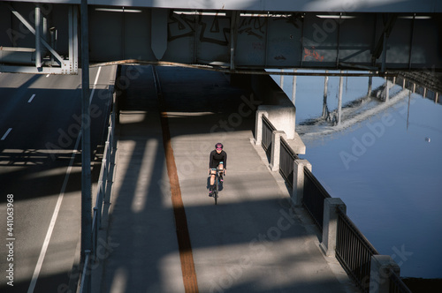 Wallpaper Mural A woman rides a bicycle along the embankment in the morning illuminated by the sun. Outdoor sports. Sports ammunition. Torontodigital.ca