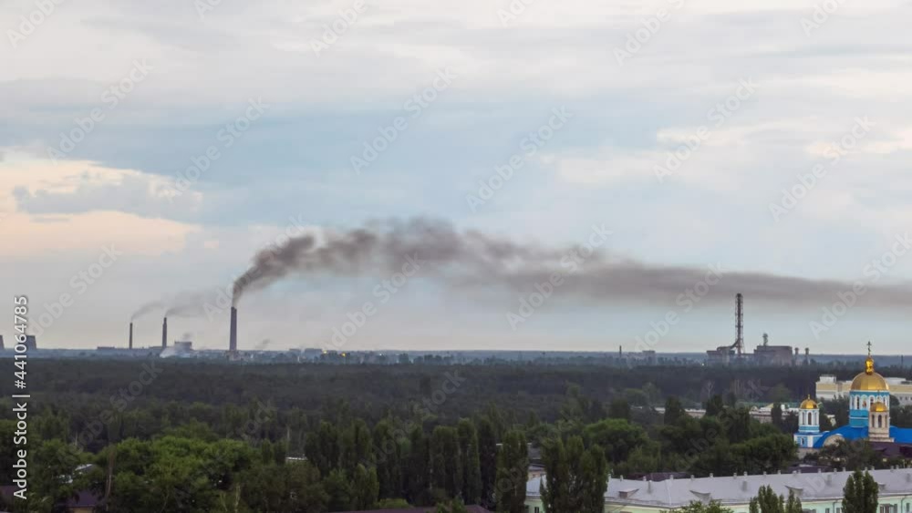 Cityscape on summer day with residential district and plant on a background filmed in timelapse. Factory with pipes is emitting smoke and polluting air. Ecological problems and dirty atmosphere theme. Cityscape on summer day with residential district and plant on a background filmed in timelapse. Factory with pipes is emitting smoke and polluting air. Ecological problems and dirty atmosphere theme.