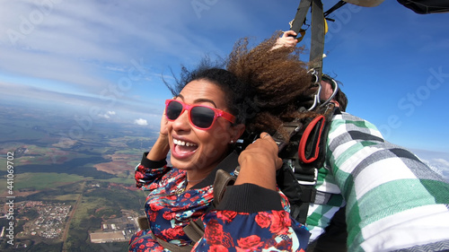 Beautiful black woman practicing skydiving. Tandem jump with selfie image.