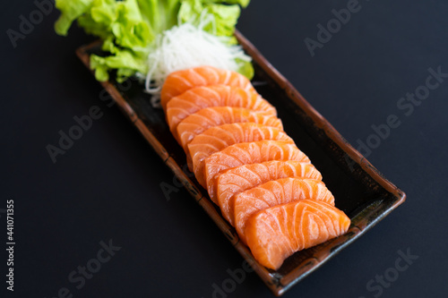 Salmon Sashimi in Japanese buffet restaurant menu.Fresh salmon fillet on black plate salmon slices.Asian people eating sashimi set Japan restaurant.salmon sashimi.Asian Food Menu.seafood sashimi.