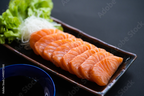 Salmon Sashimi in Japanese buffet restaurant menu.Fresh salmon fillet on black plate salmon slices.Asian people eating sashimi set Japan restaurant.salmon sashimi.Asian Food Menu.seafood sashimi.