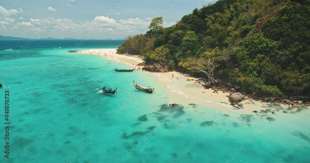 Travel to Thailand paradise tropic island. Boat tour to Phi Phi Leh. Turquoise water, traditional wooden long tail boats, white sand beach. Wild landscape. Exotic summer vacation. Drone flight aerial
