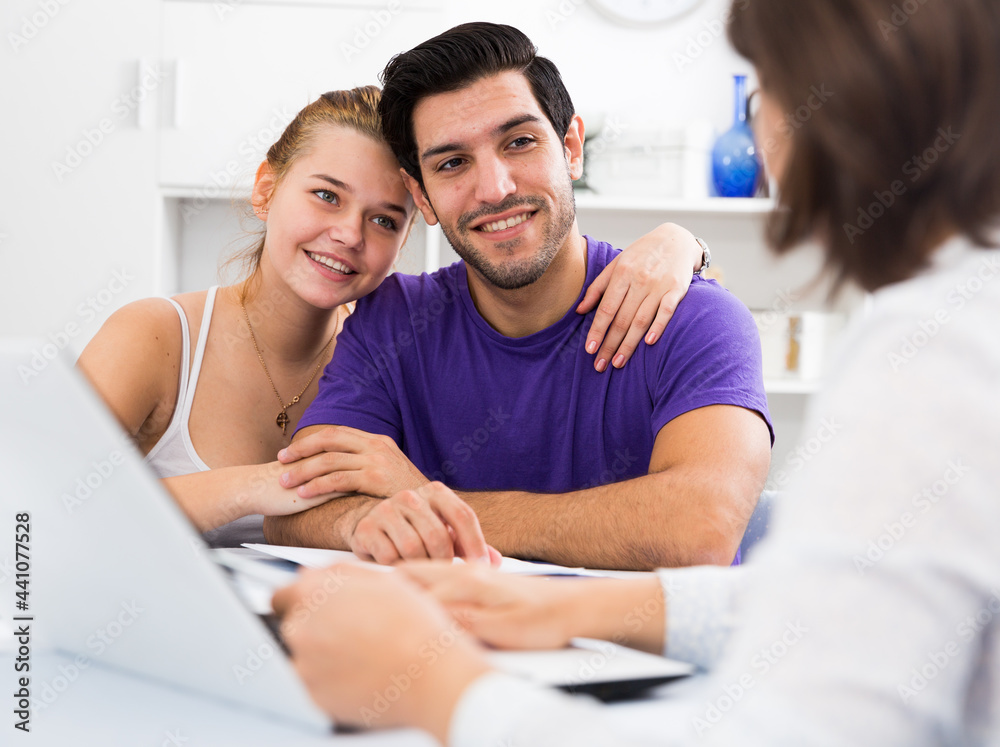 Obraz premium Loving couple discussing house reconstruction project with female designer at home