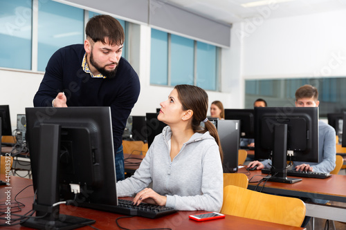 Teacher helping student in computer class in university