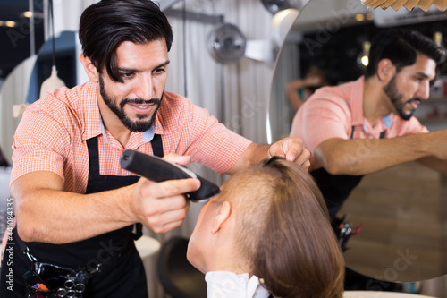 .Cheerful male professional shaving female's hair in hairdressing salon