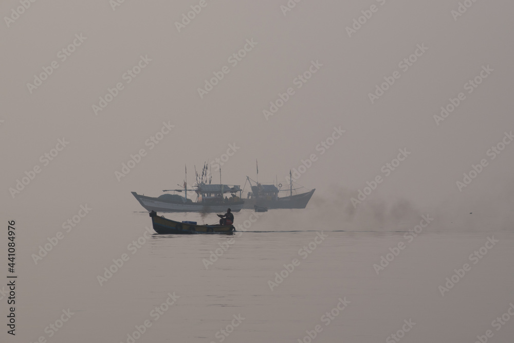 Fisherman riding boat with smoke in sea water Fisherman riding boat with smoke in sea water