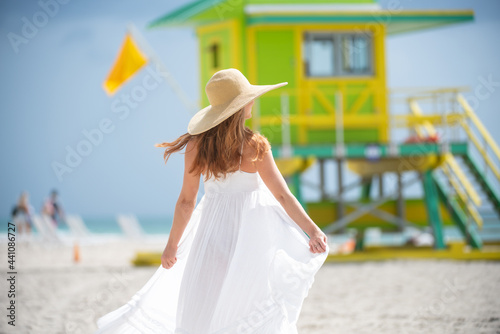 Back view of beautiful woman walking on the miami south beach. Girl walk near miami beach lifeguard.