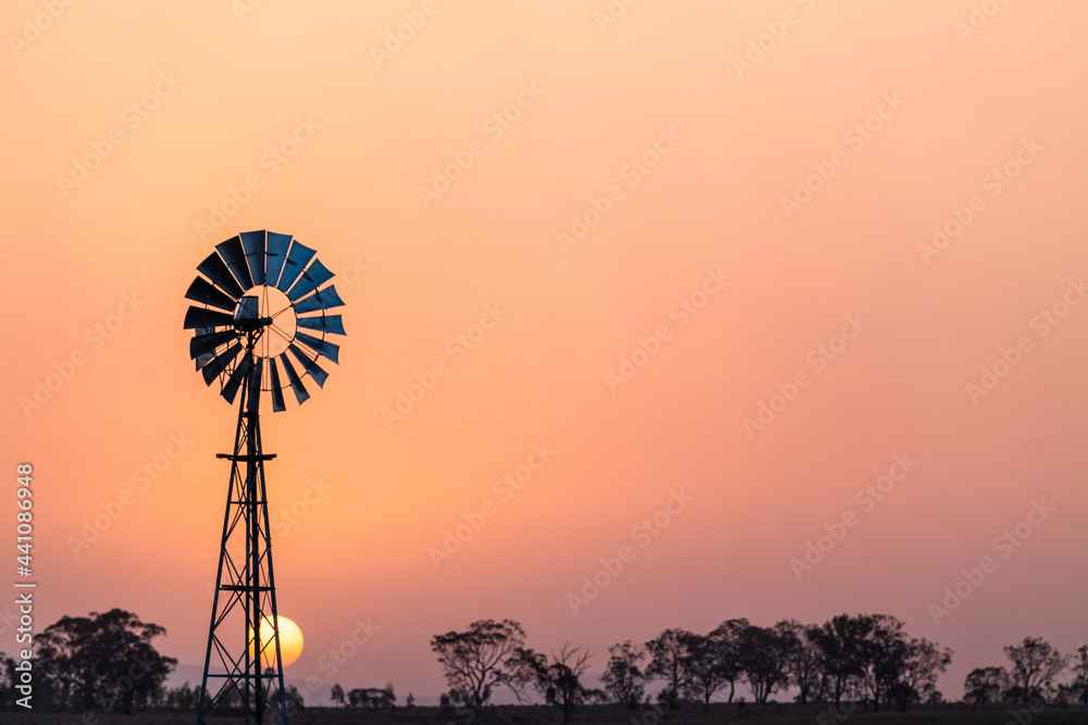 Windmill against a smoky sunset in drought conditions Windmill against a smoky sunset in drought conditions
