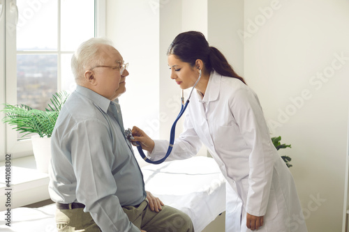 Doctor putting stethoscope on patient chest listen heartbeat and lungs breath. Elderly male person exam at hospital ward. Cardiologist physician appointment. Nursing home clinic service for pensioner photo