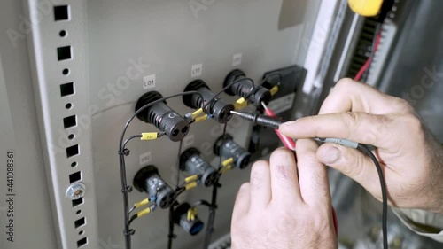 Electricians hands testing current electric in control panel