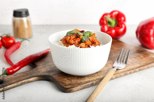 Bowl with tasty chili con carne and rice on light background