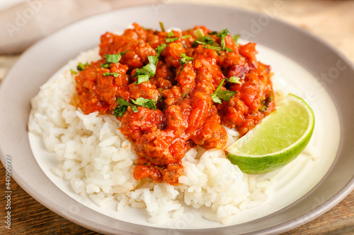 Plate with tasty chili con carne, rice and lime on table, closeup