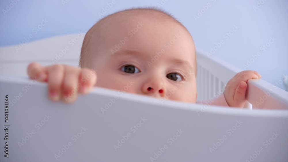 The baby peeks out from behind the headboard. close-up. joyful baby. happy childhood The baby peeks out from behind the headboard. close-up. joyful baby. happy childhood